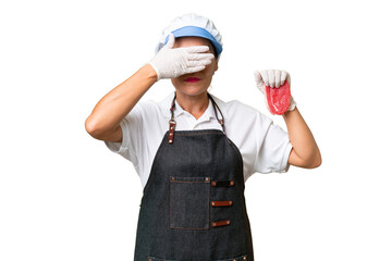 Butcher woman wearing an apron and serving fresh cut meat over isolated background covering eyes by hands. Do not want to see something