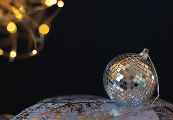 Silver disco mirror ball Christmas bauble close up with selective focus against black background. Xmas or winter holiday celebration concept. New Year greeting card with copy space for the text