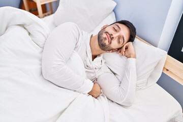 Fototapeta premium Young hispanic man lying on bed sleeping at bedroom