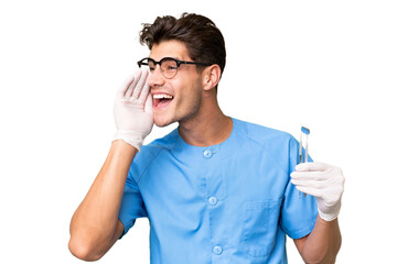 Young dentist man holding tools over isolated background shouting with mouth wide open to the side