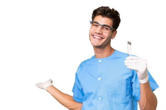 Young dentist man holding tools over isolated background extending hands to the side for inviting to come