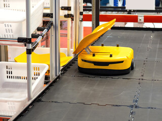 Automatic placement goods in warehouse. Yellow warehouse cart robot. Robot for automation of...