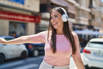 Young beautiful hispanic woman smiling confident listening to music at street