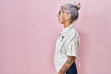 Middle age woman with grey hair wearing artist look looking to side, relax profile pose with natural face with confident smile.