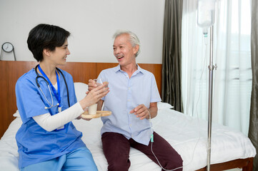 Obraz premium Asian nurse giving an elderly medicine at senior healthcare center.