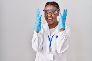 African american woman with braids wearing scientist robe celebrating mad and crazy for success...
