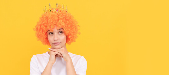 egoistic funny girl with fancy look wearing orange hair wig and princess crown, imagining. Woman...