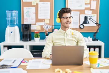 Young hispanic man business worker using laptop and headphones working at office