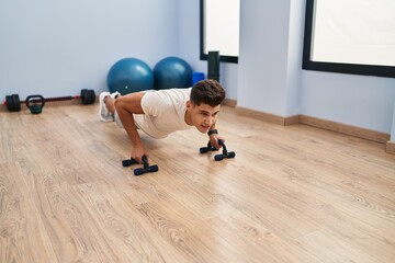 Young hispanic man training push up at sport center