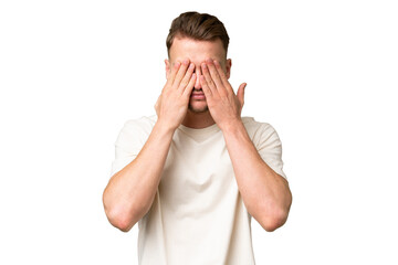 Young blonde caucasian man over isolated background covering eyes by hands