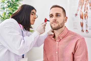 Man and woman doctor and patient having medical consultation examining ear at clinic