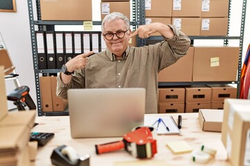 Senior caucasian man working at small business ecommerce with laptop smiling cheerful showing and pointing with fingers teeth and mouth. dental health concept.