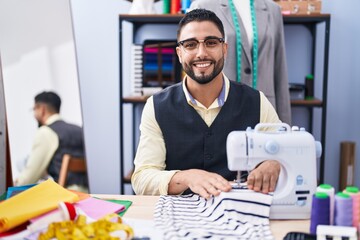 Fototapeta na wymiar Young arab man tailor smiling confident using sewing machine at clothing factory