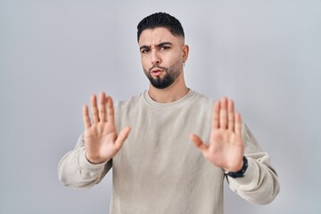 Naklejka premium Young handsome man standing over isolated background moving away hands palms showing refusal and denial with afraid and disgusting expression. stop and forbidden.