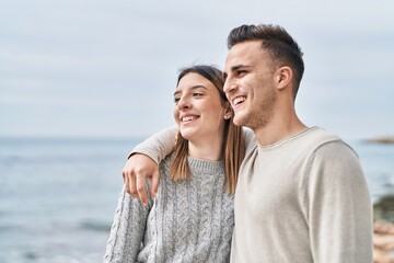 Man and woman couple smiling confident hugging each other at seaside