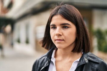 Young beautiful hispanic woman looking to the side with serious expression at street