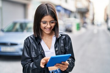 Young beautiful hispanic woman smiling confident using touchpad at street