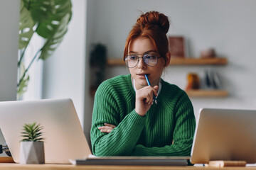 Concentrated young woman using technologies while working from home