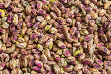 Colorful peeled raw dry pistachios, food background texture.