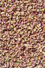 Colorful peeled raw dry pistachios, food background texture.
