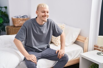 Young caucasian man smiling confident sitting on bed at bedroom