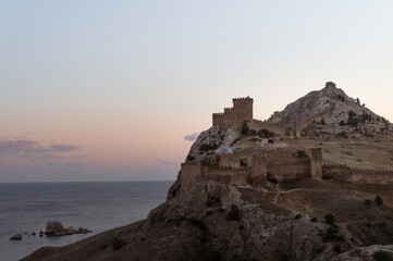 Fototapeta na wymiar ancient fortress on mountain by sea at sunset. Crimea, Sudak