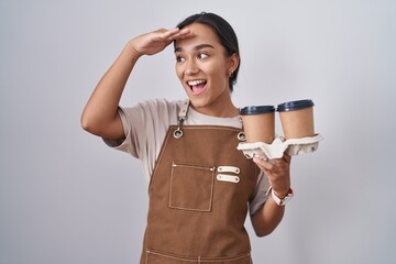 Young hispanic woman wearing professional waitress apron holding coffee very happy and smiling...
