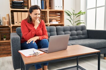 Middle age hispanic woman psychologist having online therapy session at psychology center