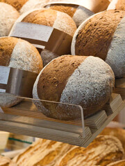 Delicious freshly baked bread loafs on display in a bakery store. Golden brown bread loafs on shelves. Bakery store interior with freshly baked products. Tasty German traditional sour-dough bread. 