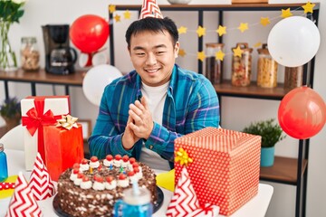 Young chinese man celebrating birthday sitting on table at home