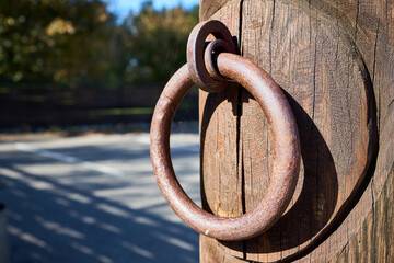 Door handle steel rusty round knocker with gossamer selective focus on brown old wooden entrance...