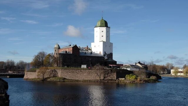 high old tower of St. Olav of the Vyborg castle on the island is reflected in the water of the Gulf of Finland on a sunny autumn day