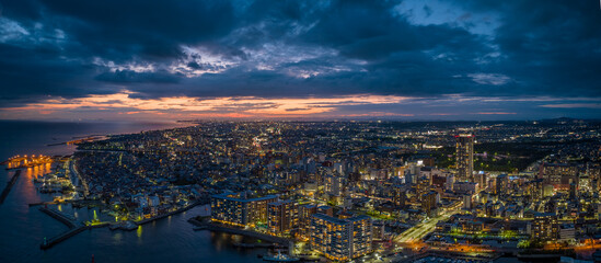 Panoramic aerial view of waterfront city at night with sunset afterglow