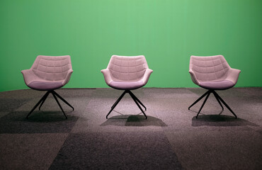 Three empty chairs in a studio with green screen