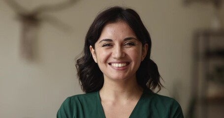 Head shot attractive young brunette woman in casual clothes and wide toothy smile standing indoors, posing staring at camera feels happy. Teacher, professional occupation person or housewife portrait - Powered by Adobe