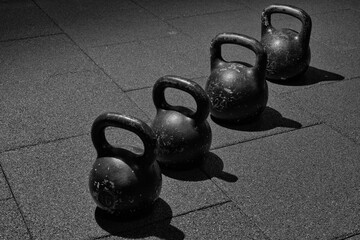Obraz na płótnie Canvas four sports kettlebells for weight training. Bodybuilding equipment. Fitness or bodybuilding concept background. black and white photography