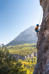 Children's rock climbing. The boy climbs a rock against the backdrop of mountains. Extreme hobby....