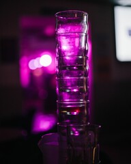 Vertical view of stacked drinking glasses before the purple lights