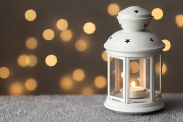 Christmas postcard with white vintage lantern and candle and warm lighs bokeh on background. Winter...