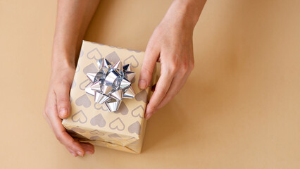 Top view of female hands holding present box package in the palms isolated over flat lay background