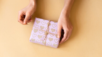 Top view of female hands holding present box package in the palms isolated over flat lay background