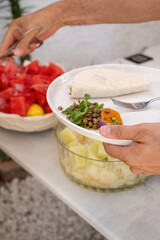 A woman buying food at the service table. the woman is taking a green lentil salad on her plate. a dining table with a focus on a green lentil salad. vegetarian nutrition.