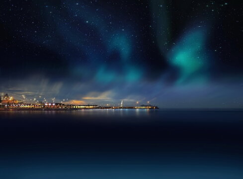Night city blurred light on horizon at sea blue water wave and Aurora borealis on starry sky