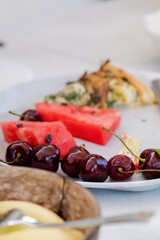 Close-up of cherries on a plate with watermelon slices and veggie pie. cherries that look fresh and tasty with their stems. vegetarian nutrition.