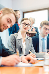 Business woman amidst team working in office looking at camera