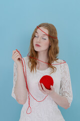 Girl hold a red thread knot. Portrait on blue
