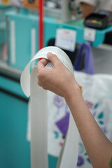 Hand of people is holding a very long paper bill, checking the detail and preparing to pay the...