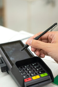People hand is using digital pen to signing on the credit card reader screen during transaction the payment. Business and technology action, selective focus.
