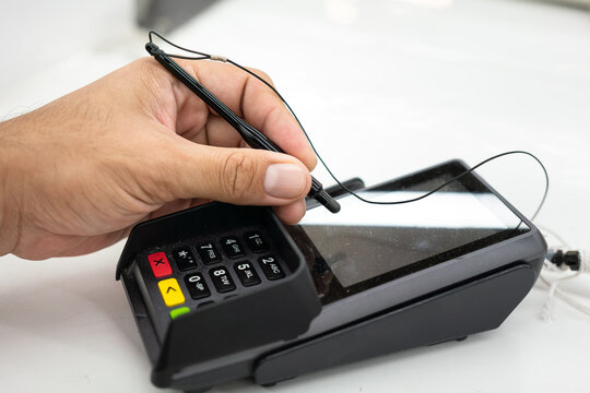 People hand is using digital pen to signing on the credit card reader screen during transaction the payment. Business and technology action, selective focus.