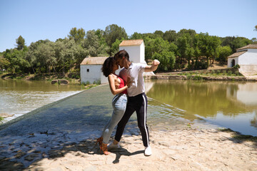 latin loving couple dancing social dance, kizomba, taraxia bachata, semba in the park next to the...